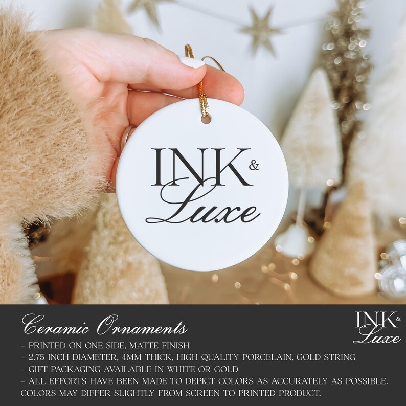 May include: A round white ceramic ornament featuring the black text INK & Luxe printed in the center. The ornament has a hole at the top with a gold string attached for hanging. The product is 2.75 inches in diameter and 4mm thick.