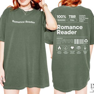 May include: A green t-shirt with the text "Romance Reader" printed on the front and back. The back of the shirt also includes the text "100% TBR Reading Full" and "Contents include a lover of many romance tropes".