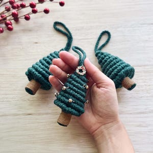 May include: Three green rope Christmas tree ornaments with gold bells and a gold wreath charm.