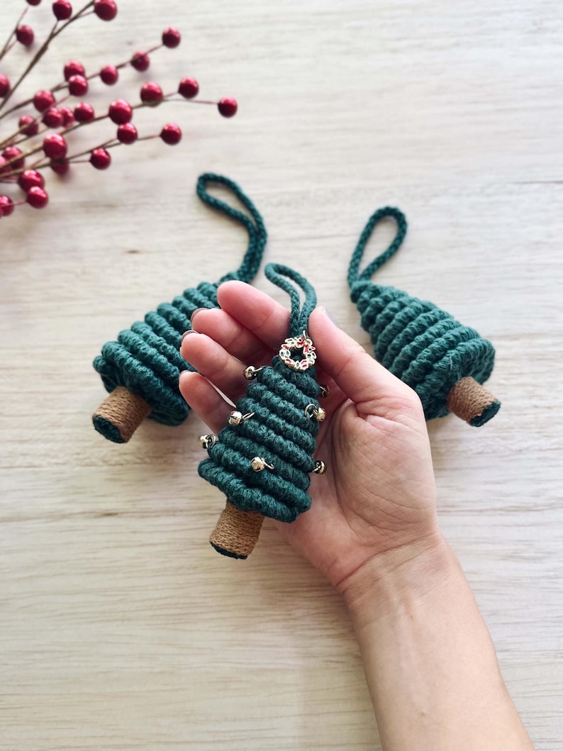 May include: Three green rope Christmas tree ornaments with gold bells and a gold wreath charm.