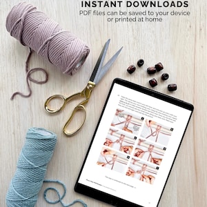 May include: A craft supplies arrangement featuring two spools of cord, one mauve and one teal, gold scissors, wooden beads, and a tablet displaying instructions. Text reads: "ALL PATTERNS ARE INSTANT DOWNLOADS. PDF files can be saved to your device or printed at home."