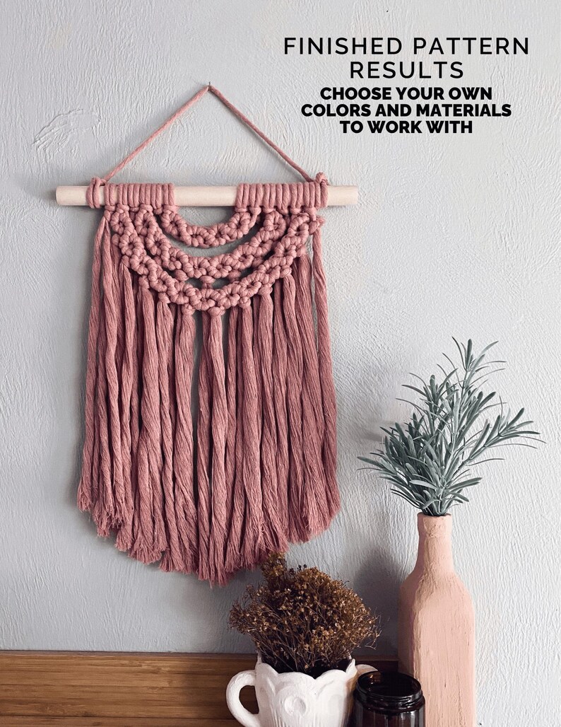May include: A dusty rose macrame wall hanging with a wooden dowel and hanging cord. The macrame features a half-circle design with long fringe. Text reads: FINISHED PATTERN RESULTS. CHOOSE YOUR OWN COLORS AND MATERIALS TO WORK WITH.