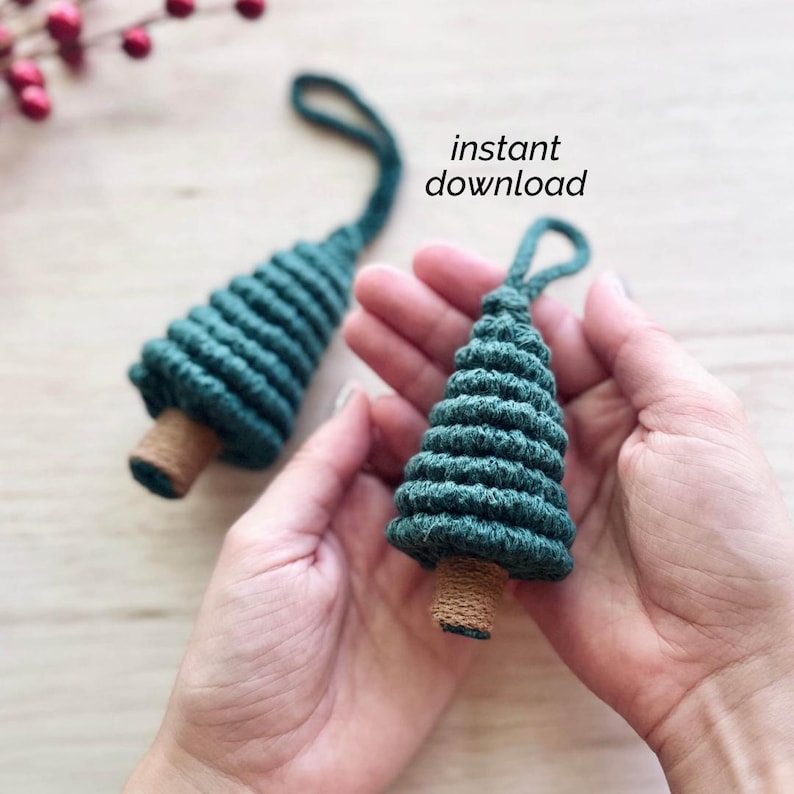 May include: Two green crocheted Christmas tree ornaments with brown bases. The ornaments are held in a person's hands. The text "instant download" is visible in the image.