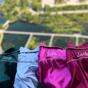 May include: Five satin pyjamas in different colours with white embroidered names: Luna, Grace, Lola, and Jack.