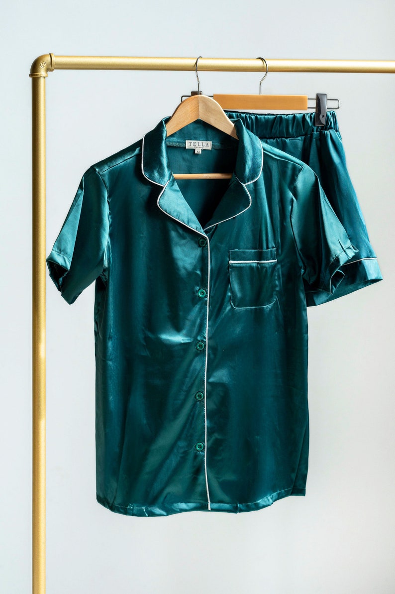 K&ouml;nnte beinhalten: Ein dunkel-smaragdgr&uuml;nes Pyjama-Set, bestehend aus einem kurz&auml;rmeligen Hemd mit Knopfleiste, Reverskragen und Brusttasche sowie einer passenden Shorts. Das Set ist mit einer wei&szlig;en Paspelierung am Kragen, der Tasche und der Knopfleiste versehen.
