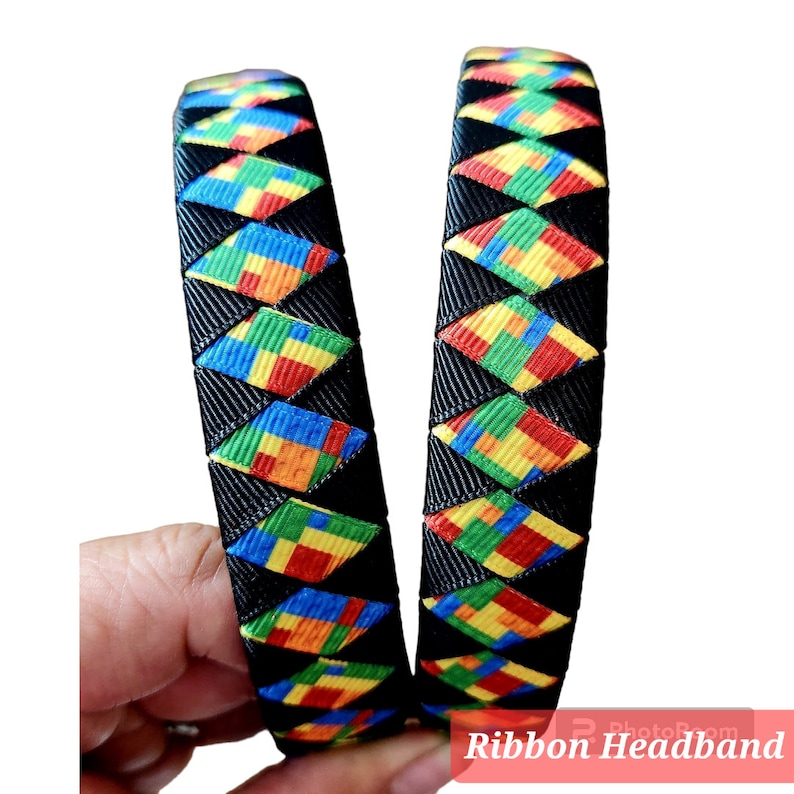 May include: Two black ribbon headbands with a colorful pattern of red, yellow, blue, and green squares. The pattern resembles building blocks.