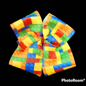 May include: A large yellow, red, blue, and green bow with a Lego block pattern.