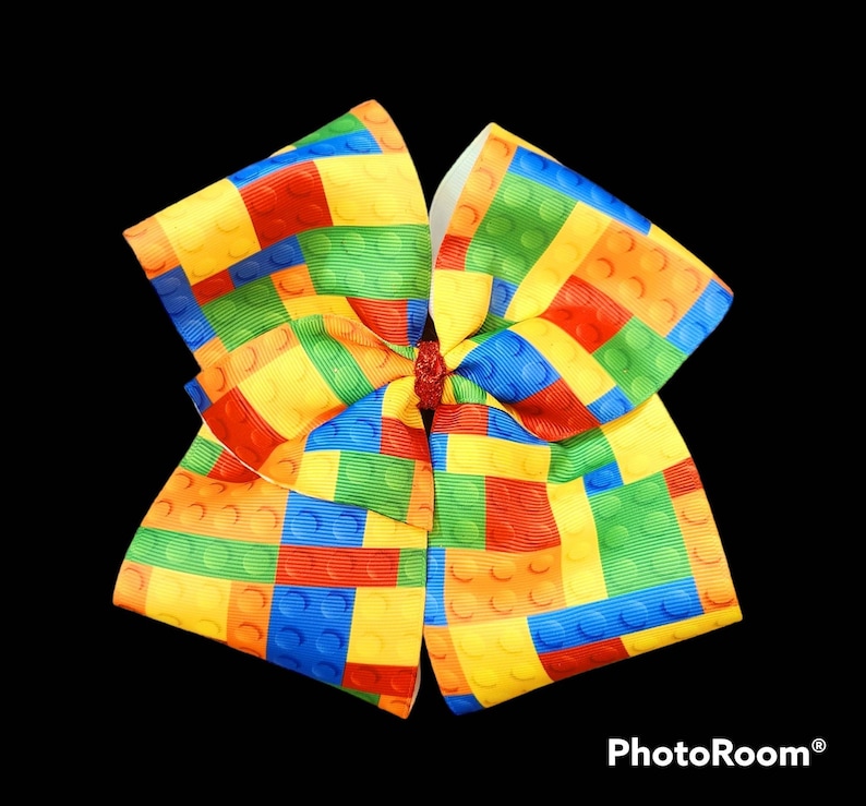 May include: A large yellow, red, blue, and green bow with a Lego block pattern.