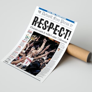 Może przedstawiać: Plakat z gazety upamiętniający Detroit Pistons, mistrz&oacute;w NBA w 2004 roku. Nagł&oacute;wek brzmi "R-E-S-P-E-C-T!" z podtytułem "Pistons earn it with Game 5 blowout". Plakat jest zwinięty z brązową tekturową tubą.