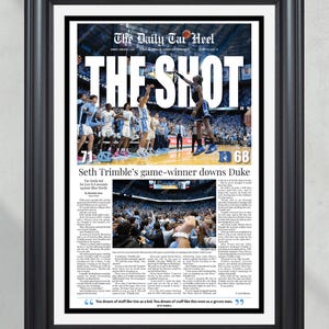 Può includere: Stampa incorniciata di una prima pagina di giornale intitolata "The Daily Tar Heel" con il titolo "THE SHOT". L'immagine mostra una partita di basket con il punteggio 71-68. Il testo recita "Seth Trimble's game-winner downs Duke."