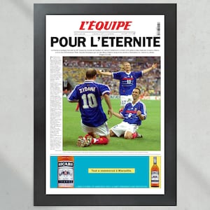May include: A vintage newspaper clipping from L'Equipe, a French sports newspaper, with the headline "Pour l'Eternite" (For Eternity). The image shows French soccer players Zinedine Zidane and Emmanuel Petit celebrating their victory in the 1998 World Cup final. The newspaper is framed in black and features a Ricard ad at the bottom.