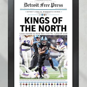 May include: Framed Detroit Free Press newspaper front page with the headline "KINGS OF THE NORTH." The image features a football game with players in blue and purple uniforms. The text reads "Detroit Lions vs. Minnesota Vikings" and "Lions rumble to their first-ever No. 1 playoff seed."
