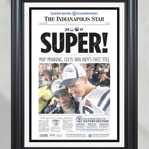 May include: Framed newspaper front page from The Indianapolis Star, celebrating the Super Bowl victory. The headline reads "SUPER!" with "MVP MANNING, COLTS WIN INDY'S FIRST TITLE." The frame is black.