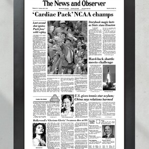 May include: A black and white newspaper clipping from The News and Observer, dated Tuesday, April 2, 1991. The headline reads "'Cardiac Pack' NCAA champs". The article discusses the University of Nevada, Las Vegas's victory in the NCAA men's basketball championship game. Other articles include "Storybook magic lasts as State stuns Houston", "Hard-luck shuttle meets challenge", "U.S. gives tennis star asylum; China says relations harmed", and "Hollywood's 'Glorious Gloria' Swanson dies at 84".