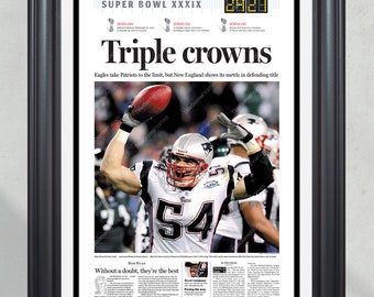 May include: A newspaper headline announcing the New England Patriots as Super Bowl XXXIX champions. The headline reads "Triple Crowns" and features a photo of a football player in a Patriots uniform celebrating with the Lombardi Trophy. The text "Eagles take Patriots to the limit, but New England shows its mettle in defending title" is also included.
