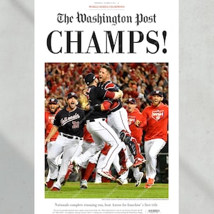 May include: A Washington Post newspaper headline announcing the Washington Nationals as World Series Champions. The headline reads "CHAMPS!" and features a photo of the team celebrating their victory. The team is wearing their red and white uniforms and are jumping and hugging each other. The photo is taken from a low angle, giving a dynamic perspective of the celebration.