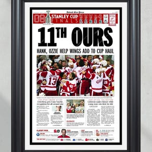 Peut inclure: Impression encadrée d'une une du journal Detroit Free Press. Le titre est « 11th OURS » avec une photo d'une équipe de hockey célébrant. Le logo des finales de la Coupe Stanley est visible. L'impression est dans un cadre noir.