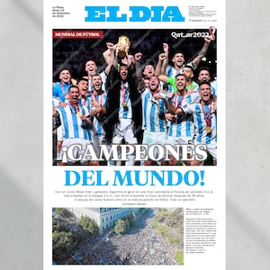 Może przedstawiać: Nagł&oacute;wek gazety głosi "&iexcl;CAMPEONES DEL MUNDO!" ze zdjęciem argentyńskiej drużyny piłkarskiej świętującej zwycięstwo w Pucharze Świata. Nagł&oacute;wek jest po hiszpańsku i oznacza "Mistrzowie Świata!"