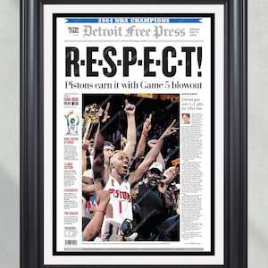 May include: Framed newspaper print celebrating the 2004 NBA Champion Detroit Pistons. The headline reads "R-E-S-P-E-C-T!" with images of players celebrating their victory. The print is in a black frame.
