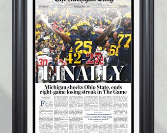 May include: Framed newspaper print with the headline "Michigan shocks Ohio State, ends eight-game losing streak in The Game." The score 42-27 is prominently displayed. The print features a black frame.