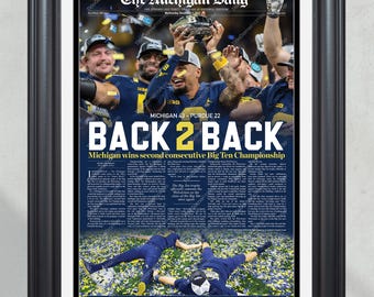 May include: A newspaper front page from The Michigan Daily, celebrating the University of Michigan Wolverines football team's victory in the Big Ten Championship. The headline reads "BACK 2 BACK" and the subheading says "Michigan wins second consecutive Big Ten Championship". The image shows the team celebrating with the trophy.