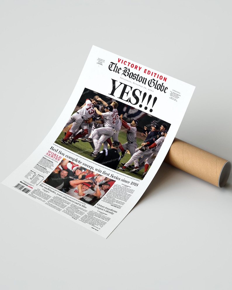 May include: A newspaper print of The Boston Globe's Victory Edition, celebrating the Red Sox's World Series win. The headline reads "YES!!!" with a photo of the team celebrating. The print is rolled up with a brown cardboard tube.