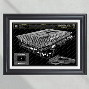 May include: A black and white architectural drawing of Lower.com Field, home of the Columbus Crew soccer team. The drawing shows the stadium's exterior and interior, including the seating areas, field, and surrounding buildings. The drawing is framed in a black frame.