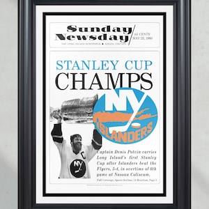 May include: A black and white newspaper clipping with a photo of a hockey player holding up the Stanley Cup trophy. The headline reads "Stanley Cup Champs" with the New York Islanders logo. The text below the photo reads "Captain Denis Potvin carries Long Island's first Stanley Cup after Islanders beat the Flyers, 5-4, in overtime of 6th game at Nassau Coliseum."