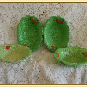 May include: Set of four green ceramic bowls with a cabbage leaf design and red tomato accents.