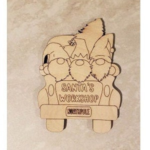 May include: Wooden cutout of a red truck with three elves in the back. The truck has the words "Santa's Workshop" and "North Pole" written on it.