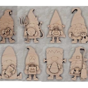 May include: A collection of eight unfinished wooden Halloween gnome cutouts. Each gnome is uniquely designed, featuring costumes like a mummy, devil, and Frankenstein. The gnomes are in various poses, holding props such as a trident, candy, and a broom.