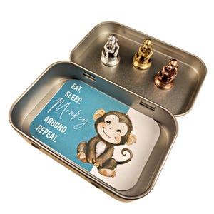 May include: A silver, gold, and bronze monkey figurine set in a tin box with a blue and white card that says "Eat, Sleep, Monkey, Around, Repeat."