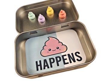 May include: A small metal tin with a light pink, smiling poop emoji and the text "HAPPENS". The tin has four small pastel-colored poop emoji charms inside.