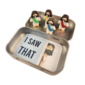 May include: A small tin box with a white card inside that says "I saw that". There are four small figurines of people wearing robes inside the tin box.