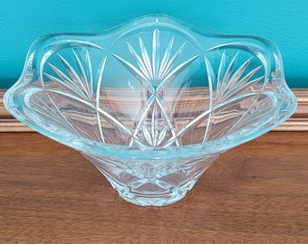May include: A clear glass bowl with a decorative cut-glass design. The bowl has a wide, shallow base and a flared rim.