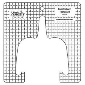 May include: A white plastic template with a pointed arc shape, marked with a grid pattern. The template is labeled "Pointed Arc Template" and has the website address "www.HandQuilters.com".