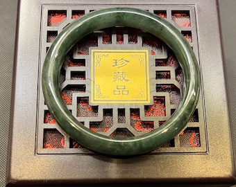 May include: A dark green jade bangle bracelet in a dark brown box with a gold label that reads "珍藏品".