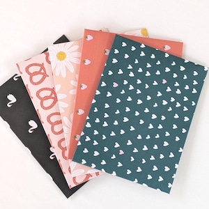 May include: Five different patterned paper sheets. The patterns include pretzels, swans, daisies, strawberries, and hearts. The sheets are all pink, white, and green.
