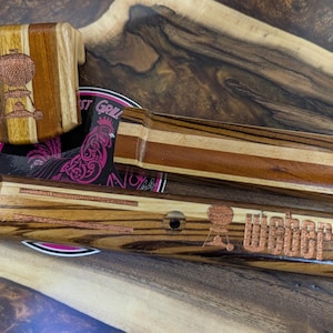 May include: Wooden barbecue accessories with a striped design. The set includes a box, a long rectangular piece, and a piece with the word "Weber" etched on it, along with a grill graphic. The accessories are made of light and dark wood.