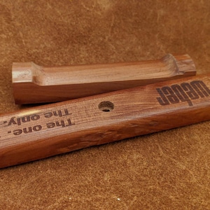 Pode incluir: Duas ferramentas de grelha de madeira com o texto "Weber" e "The one. The only." gravado na madeira. As ferramentas s&atilde;o de cor castanho m&eacute;dio e parecem novas.