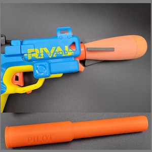 Puede incluir: Un blaster de juguete azul y amarillo con un cañón naranja. El blaster tiene la palabra "RIVAL" impresa en el lateral. El cañón es extraíble y tiene la palabra "PILOT" impresa en él.
