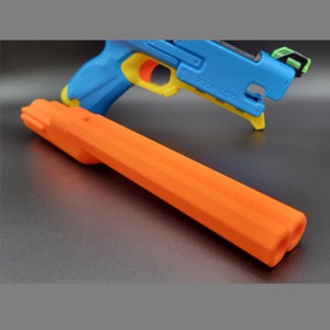 May include: An orange plastic barrel extension for a toy gun. The barrel has three holes at the end and is designed to be attached to a toy gun.