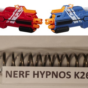 May include: A close-up of a gold-colored spring in a clear plastic bag. The bag has a white label that reads "NERF HYPNOS K26".