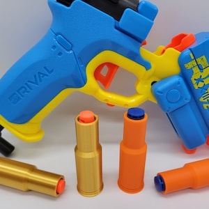 May include: A blue and yellow Nerf Rival  toy gun with a black handle and a magazine. There are four orange and gold Nerf Rival rounds next to the gun.
