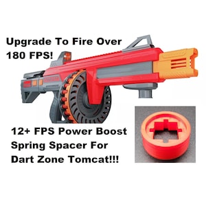 May include: Red and orange Dart Zone Tomcat toy gun with a 12+ FPS Power Boost Spring Spacer. The spacer is a red and orange plastic ring with a square hole in the center. The text "Upgrade To Fire Over 180 FPS!" is written in black text on a white background above the gun.