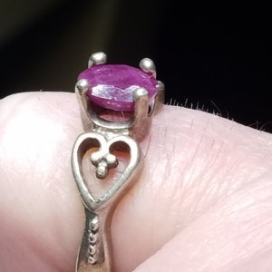 May include: A silver ring with a heart-shaped design and a pink oval gemstone.