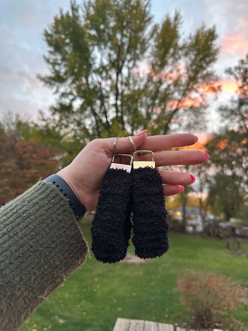 May include: Two black fuzzy keychains with gold metal rings and clasps.