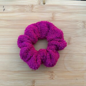 May include: A bright pink fuzzy hair scrunchie.