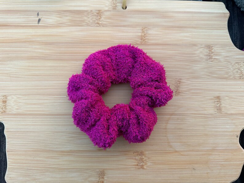May include: A bright pink fuzzy hair scrunchie.