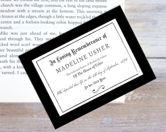 May include: A black and white framed memorial card with the text "In Loving Remembrance of MADELINE USHER" and details about her life and death. The card is on a wooden surface.
